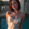 Beautiful mature woman in floral dress at luxury pool, golden hour cinematic lighting, realistic AI photography.